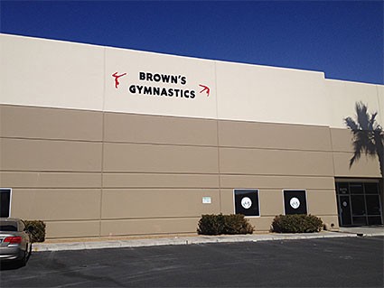 A nondescript white and tan building with the lettering &ldquo;Brown&rsquo;s Gymnastics&rdquo; at the top.